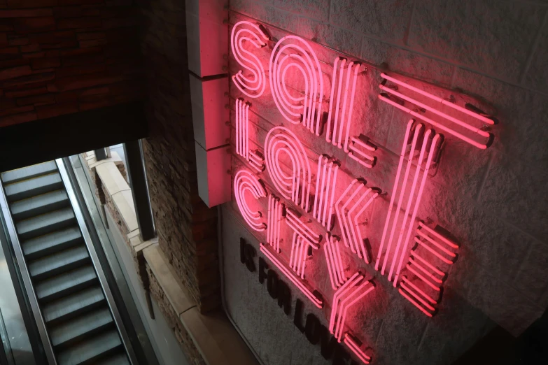 a neon sign on the side of a building, by Adam Saks, pexels, birdseye view, saloon exterior, sam leach, sake