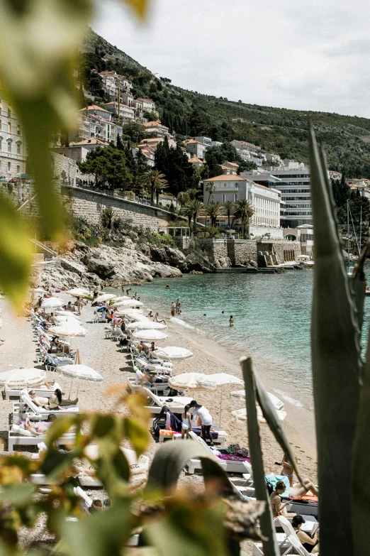 a beach filled with lots of people and umbrellas, by Daren Bader, trending on unsplash, renaissance, croatian coastline, square, foliage, dirty linen robes