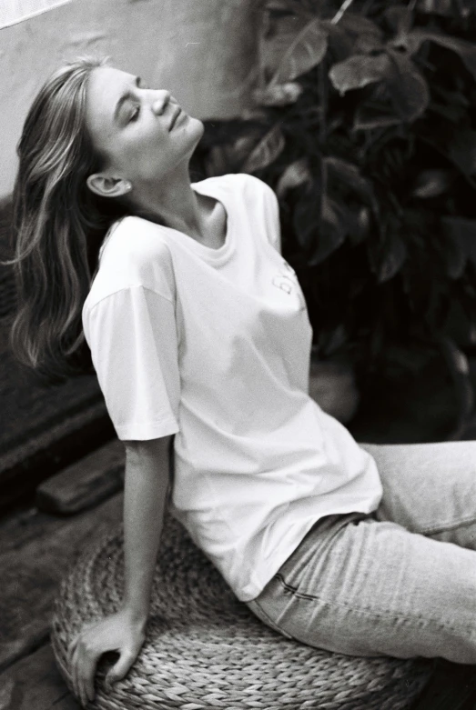 a black and white photo of a woman sitting on a chair, instagram, happening, plain white tshirt, relaxed style, baggy, supermodel