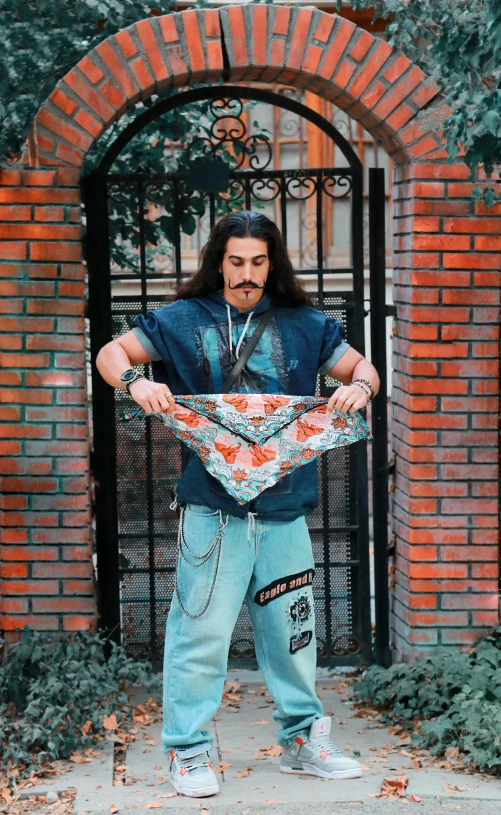 a man that is standing in front of a brick wall, an album cover, inspired by Dave Arredondo, bandana, baggy pants, adam driver, patterned clothing