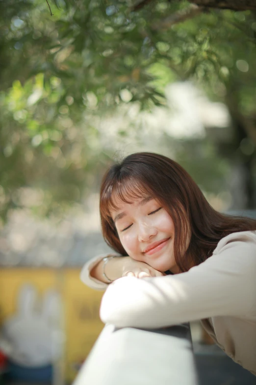 a woman leaning on a rail with her eyes closed, inspired by Kim Du-ryang, pexels contest winner, happening, smiling girl, resting head on hands, profile image, resting on a pillow