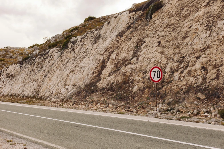 a red and white sign sitting on the side of a road, by Francesco Furini, unsplash, hyperrealism, geological strata, cyprus, speed, instagram post