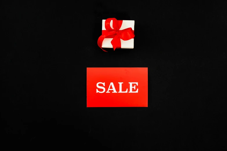 a white gift box with a red ribbon and a sale sign on a black background, a photo, by Emma Andijewska, pexels contest winner, bauhaus, a small, thumbnail, small, black