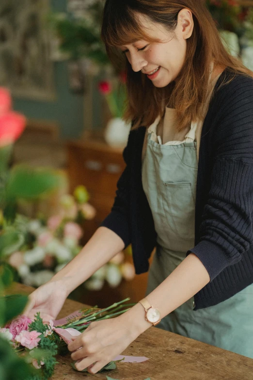 a woman arranging flowers in a flower shop, by Jessie Algie, trending on unsplash, wearing an apron, low detail, rosa bonheurn, studio photo