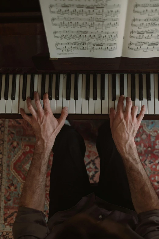 an overhead view of a person playing a piano, by Leo Michelson, cinematic full shot, sitting with wrists together, ignant, fibbonacci