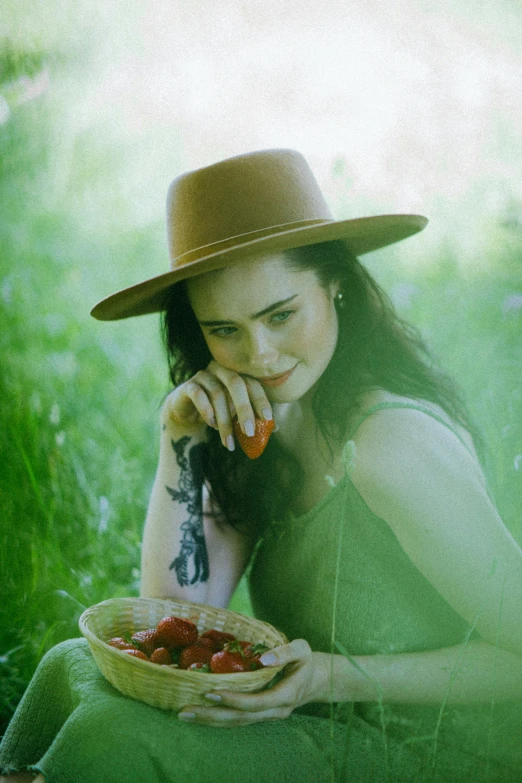 a woman sitting in the grass with a bowl of strawberries, inspired by Oleg Oprisco, pexels contest winner, lucy hale, with hat, eva green, on a farm