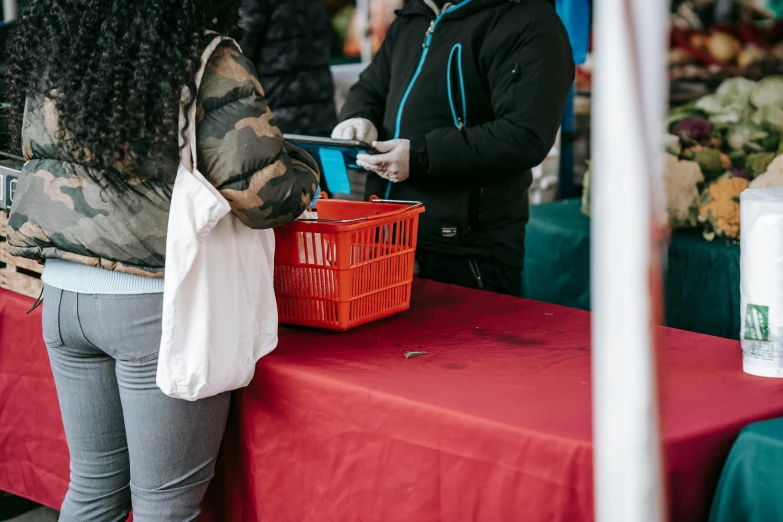 a couple of women standing next to each other at a table, pexels contest winner, private press, getting groceries, wearing a red hoodie, square, promotional image