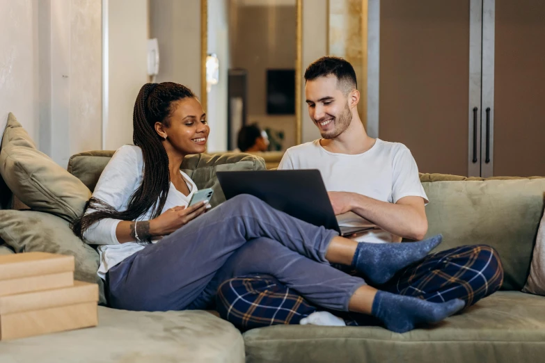 a man and woman sitting on a couch looking at a laptop, trending on pexels, avatar image, raphael lecoste, high quality image, laying down