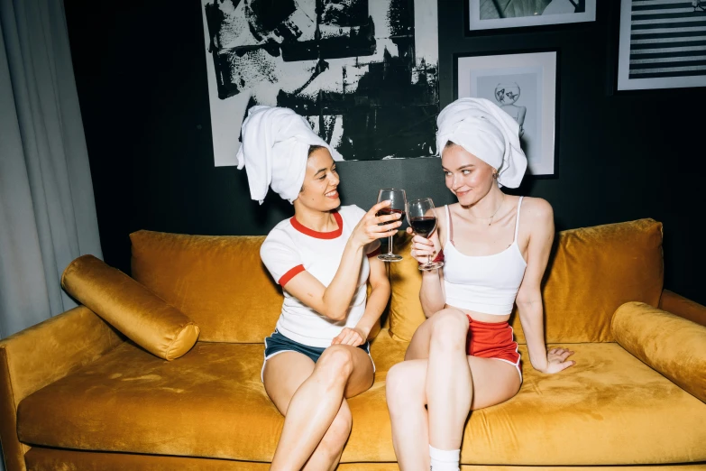 a couple of women sitting on top of a couch, by Julia Pishtar, pexels, renaissance, wearing a white bathing cap, nightlife, themed after wine, wearing a towel