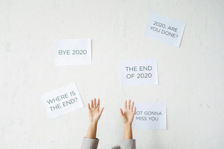 a person standing in front of a wall covered in signs, a poster, by Emma Andijewska, trending on pexels, new years eve, hand on table, with a white background, imet2020