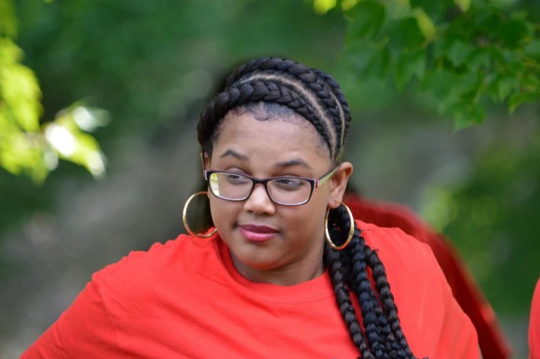 a woman in a red shirt talking on a cell phone, by Washington Allston, pexels contest winner, cornrows braids, huge chin, lush surroundings, avatar image