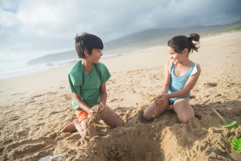 a couple of kids sitting on top of a sandy beach, profile image, play, hawaii, regular build