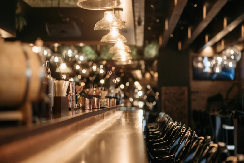 a row of wine glasses sitting on top of a bar, multiple lights, speakeasy, thumbnail, facing away