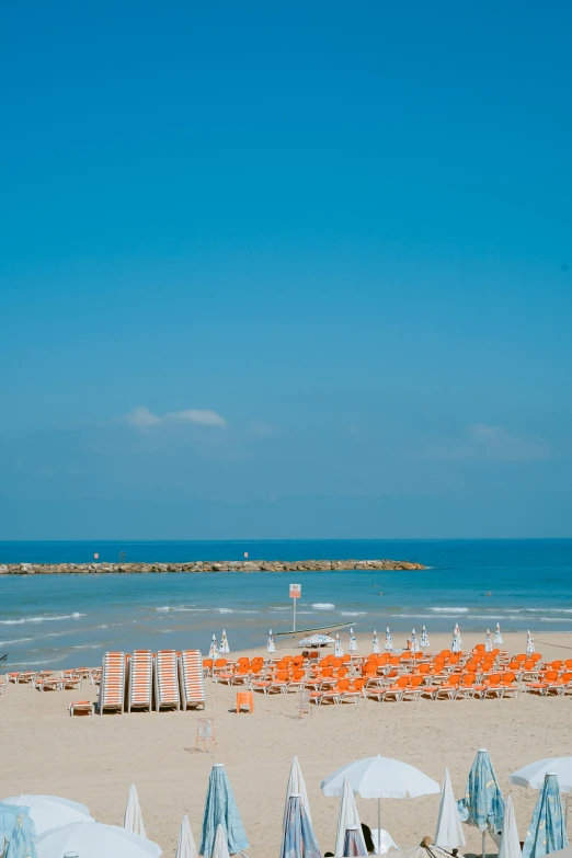 a beach filled with lots of umbrellas and chairs, tel aviv under rocket attack, orange and blue sky, square, medium long shot