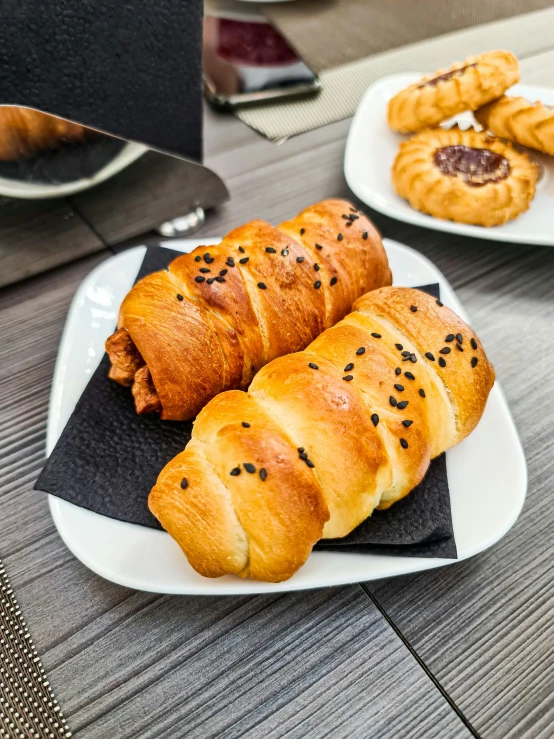 a white plate topped with croissants on top of a wooden table, momoshiki ōtsutsuki, or black, animal - shaped bread, 6 pack