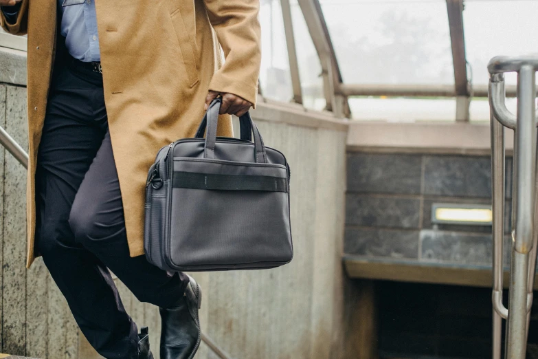 a man walking up a flight of stairs carrying a briefcase, a picture, by Carey Morris, unsplash, in gunmetal grey, full front view, carefully crafted, multi - layer