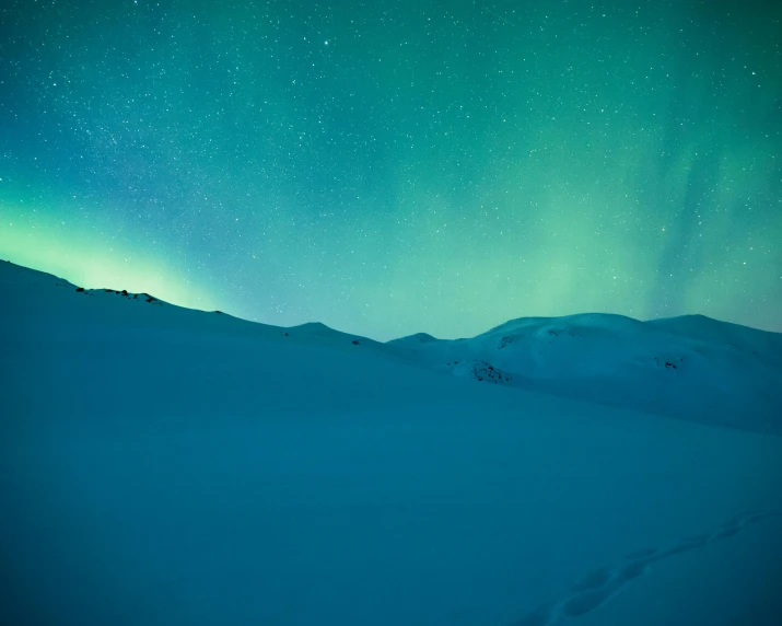 a person standing on top of a snow covered slope, an album cover, pexels contest winner, hurufiyya, blue and green light, antartic night, greens and blues, panels