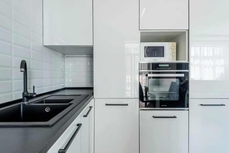 a kitchen with white cabinets and black counter tops, by Adam Marczyński, pexels contest winner, bauhaus, gloss finish, oven, modern minimalist f 2 0, lacquered