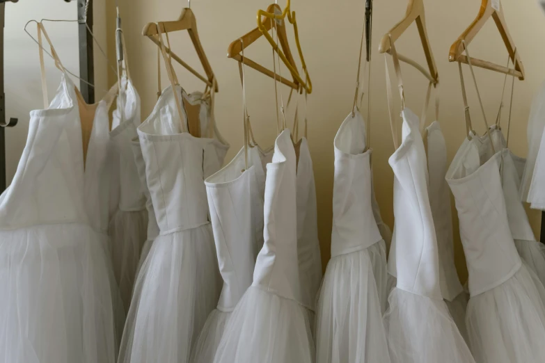 a row of wedding dresses hanging on a rack, inspired by Vanessa Beecroft, trending on unsplash, dressed as a ballerina, still from film, white uniform, finely painted