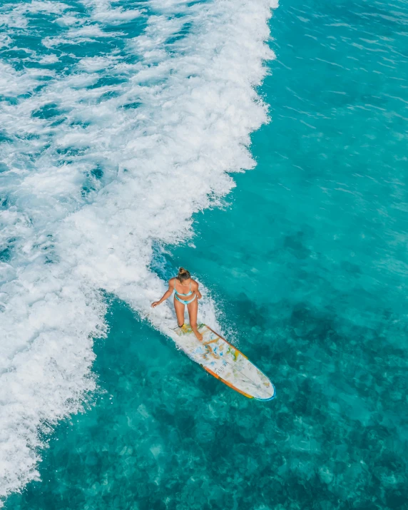 a woman riding a wave on top of a surfboard, crystal clear blue water, thumbnail, flatlay, standing on a beach in boracay
