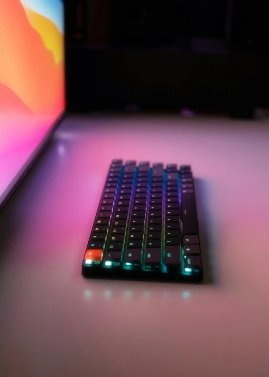 a keyboard sitting on top of a table next to a laptop, iridescent glowing chips, orange teal lighting, xqc, high res 8k