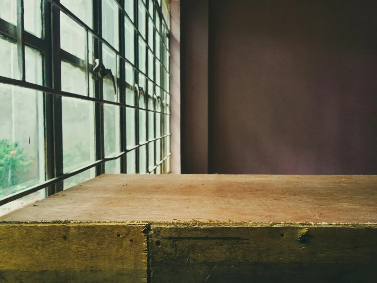 a wooden table sitting in front of a window, an album cover, unsplash, background image, [[empty warehouse]] background, gaze down, post grunge