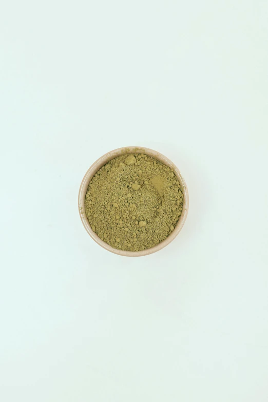 a bowl filled with green powder on top of a white table, golden ration, detailed product image, mild, frontal shot