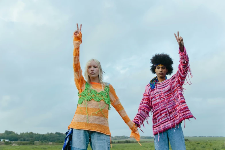 a couple of women standing on top of a lush green field, trending on pexels, renaissance, wearing a colorful coogi sweater, anya taylor joy, peace sign, margiela campaign