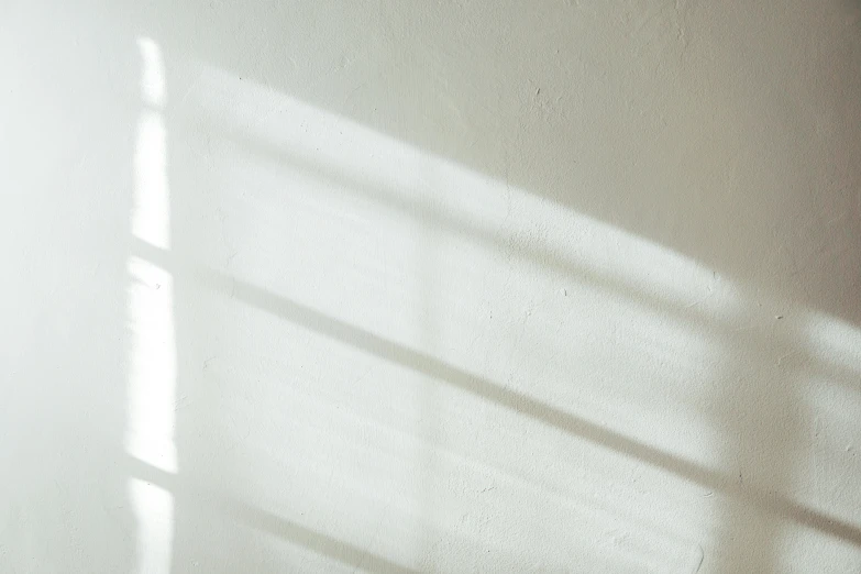 a cat laying on top of a bed next to a window, pexels contest winner, light and space, shadow gradient, background image, white wall, beam of light