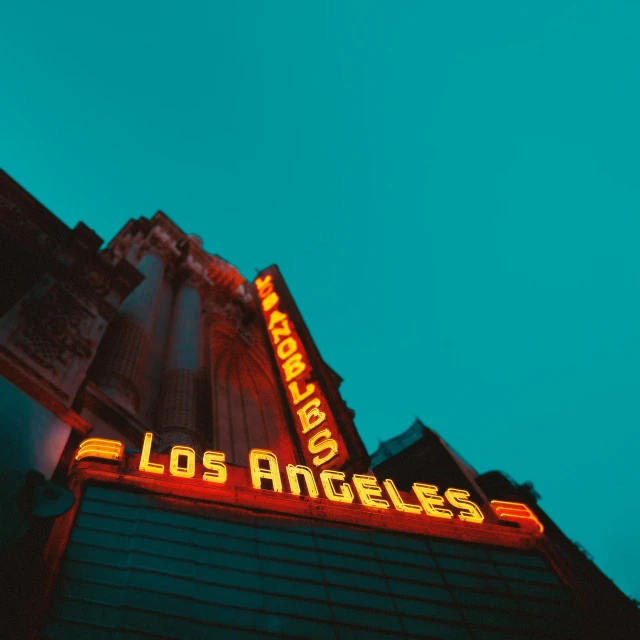 a neon sign on the side of a building, inspired by L. A. Ring, pexels contest winner, los angelos, cinematic view from lower angle, temples, teal sky
