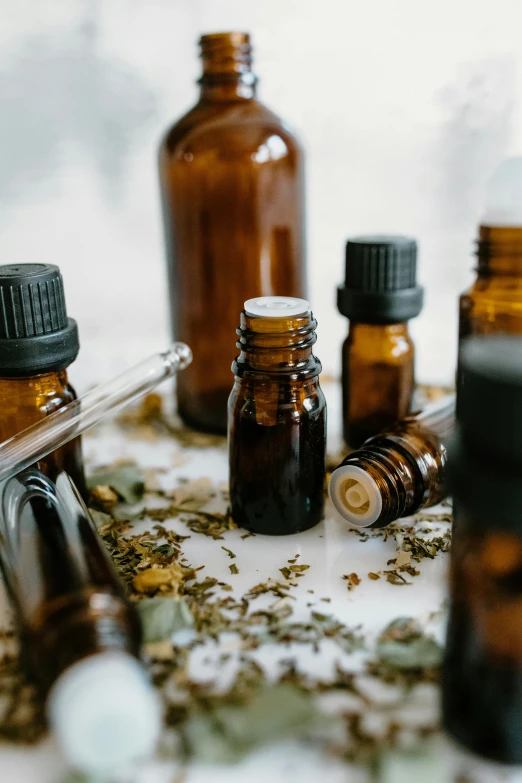 a table topped with bottles filled with different types of essential oils, by Daniel Lieske, trending on pexels, portrait photo, brown, hemp, made of liquid