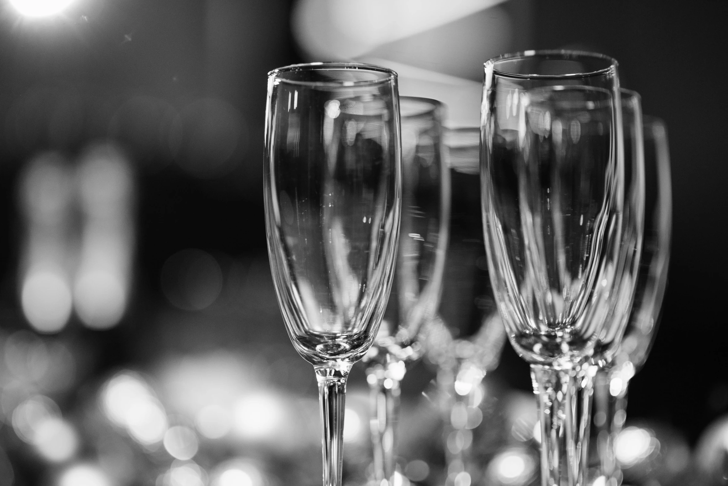a couple of wine glasses sitting on top of a table, a black and white photo, bubbly, event, in a row, gleaming silver