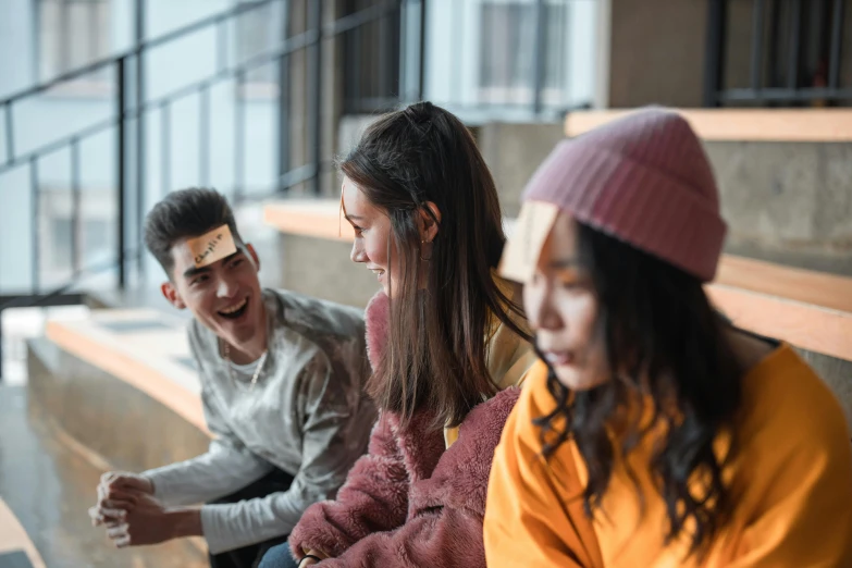 a group of people sitting next to each other on a bench, trending on pexels, playing games, avatar image, student, head bent back in laughter