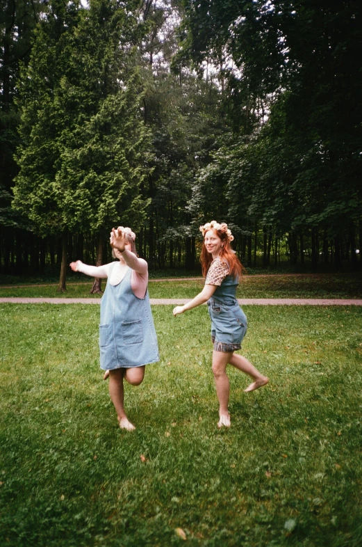 a couple of women standing on top of a lush green field, an album cover, by Anna Boch, pexels contest winner, happening, dancing a jig, walking around in forest, | 35mm|, 256435456k film