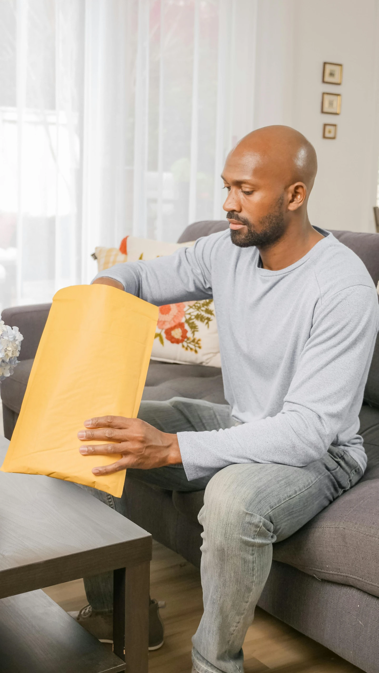 a man sitting on a couch holding a folder, by Ben Zoeller, shutterstock contest winner, private press, with yellow cloths, delivering mail, soft volume absorbation, gigachad muscular