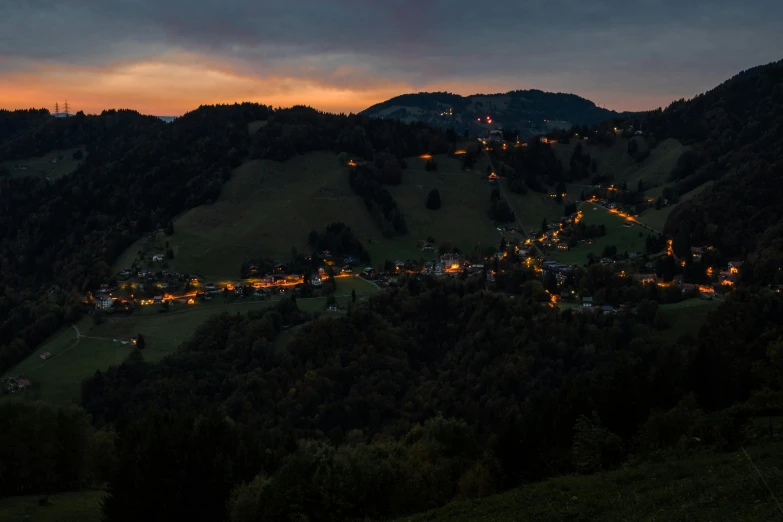 a view of a town from the top of a hill, by Sebastian Spreng, pexels contest winner, evening lights, black forest, panoramic, the middle of a valley