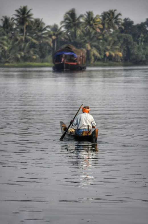 a man in a boat on a body of water, inspired by Steve McCurry, happening, kerala village, slide show, zoomed in, taken in 2 0 2 0