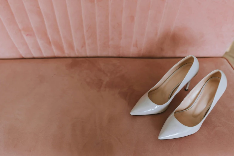 a pair of white shoes sitting on top of a pink couch, trending on pexels, bride, grey, patent leather, sharply shaped