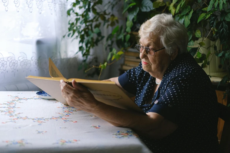 a woman sitting at a table reading a book, a portrait, pexels contest winner, looking old, 15081959 21121991 01012000 4k, profile image, looking outside