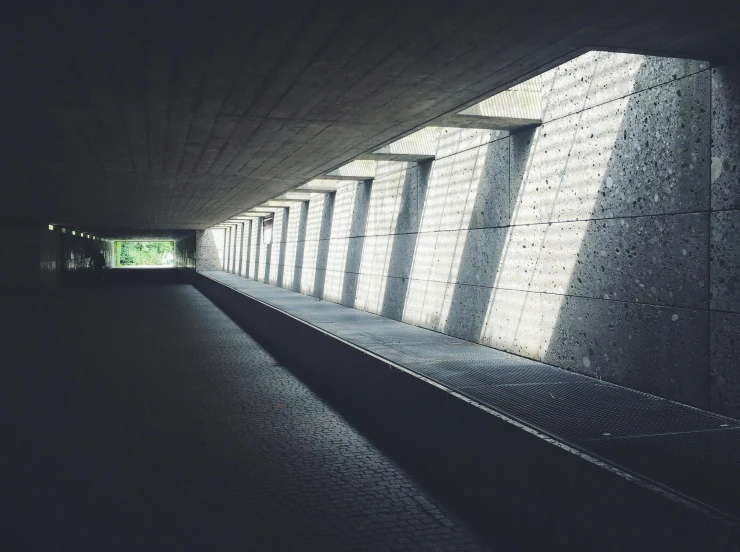 a person riding a skateboard through a tunnel, inspired by Tadao Ando, unsplash contest winner, light and space, blame! brutalist architecture, rows of windows lit internally, gray concrete, pathway