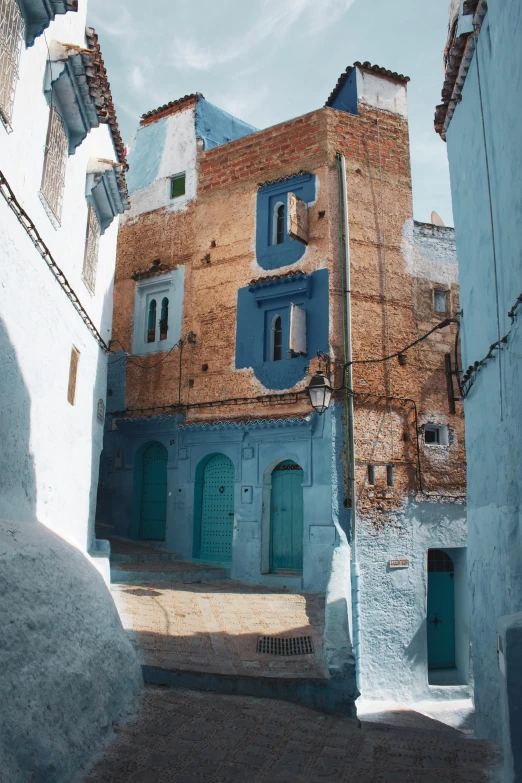 a couple of buildings that are next to each other, inspired by Alberto Morrocco, trending on unsplash, les nabis, blue robes, shady alleys, square, built on a steep hill