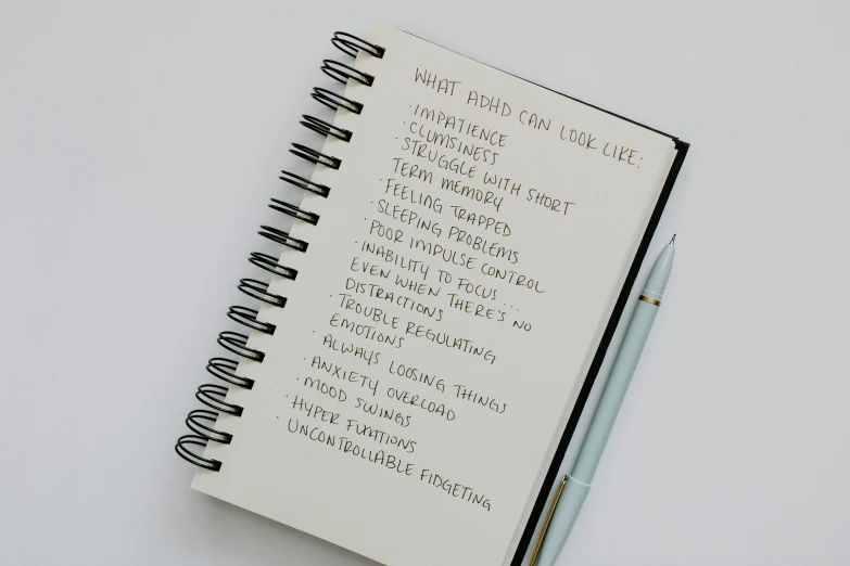 a notepad with a pen sitting on top of it, with full descriptions, looking away from the camera, listing image, lost look