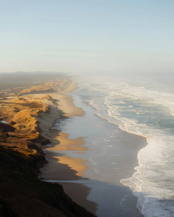 a view of the ocean from the top of a hill, by Jessie Algie, pexels contest winner, majestic dunes, te pae, flowing cape, warm glow