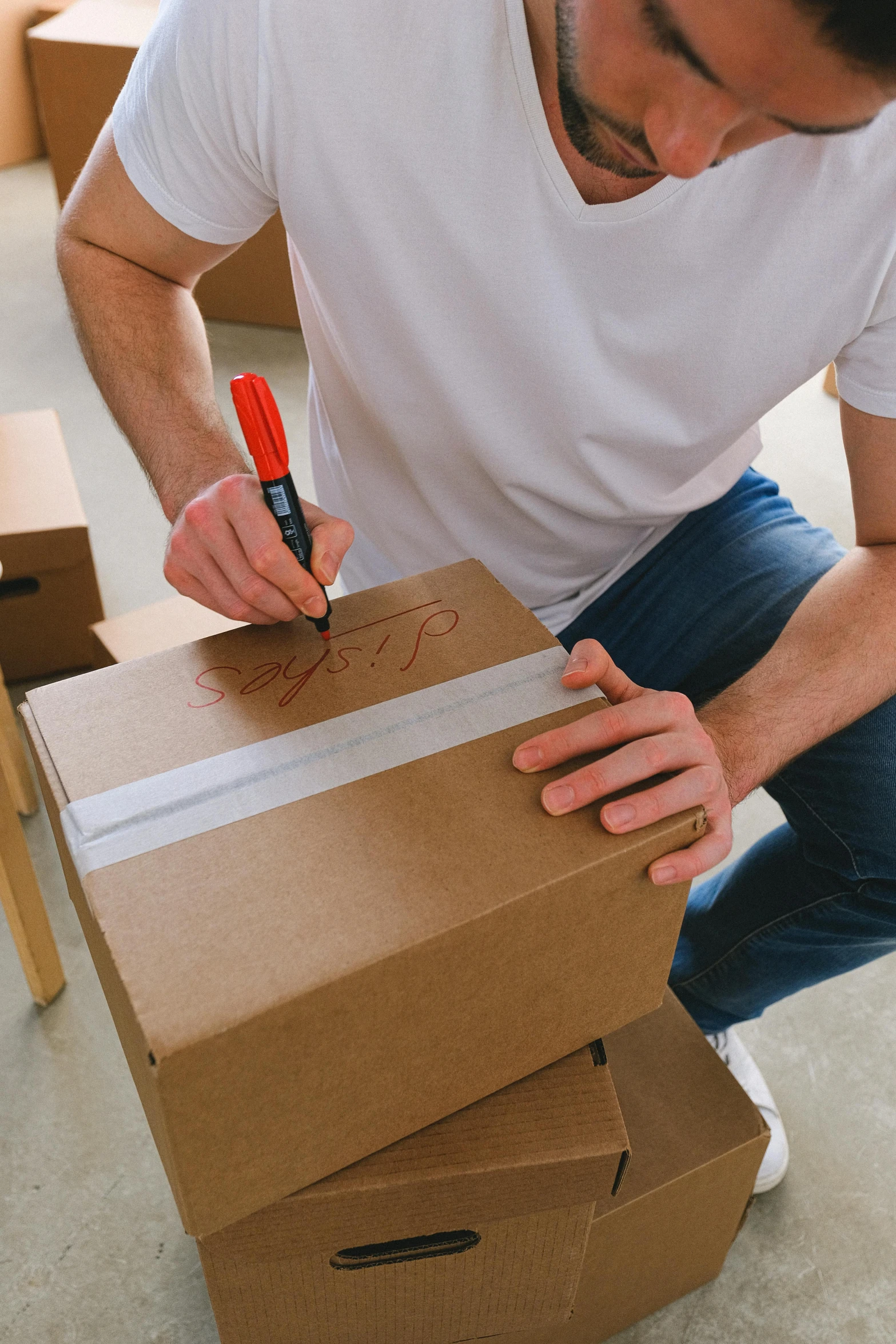 a man sitting on the floor cutting a piece of cardboard, pexels contest winner, temporary art, signature on the bottom, delivering parsel box, wire management, listing image