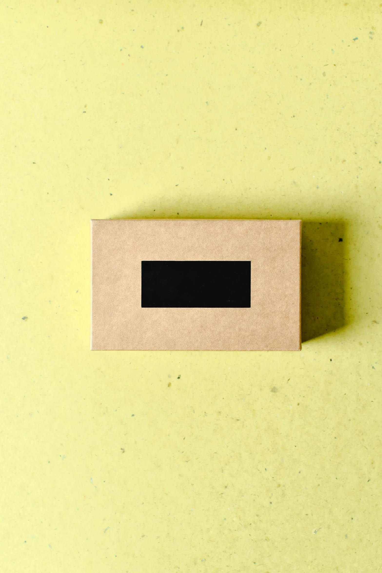 a box sitting on top of a yellow surface, thumbnail, craft, matte black paper, label