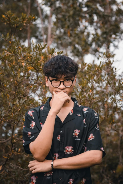 a man with glasses standing in front of a bush, inspired by Reuben Tam, unsplash, male ulzzang, patterned clothing, discord profile picture, he is about 20 years old | short