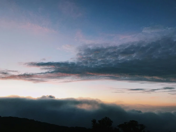 a person standing on top of a hill under a cloudy sky, a picture, unsplash contest winner, romanticism, humid evening, layered stratocumulus clouds, predawn, instagram post