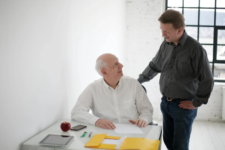 a man standing next to a man sitting at a table, unsplash, two frail, on white paper, uploaded, without text
