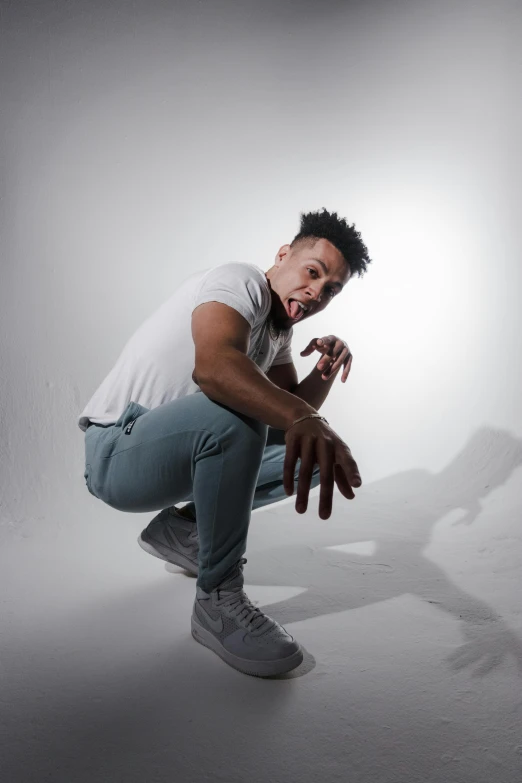 a man squatting in front of a white background, inspired by Gerald Kelly, trending on pexels, doing a sassy pose, xxxtentacion, dark backdrop, bounce lighting