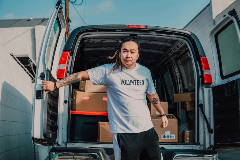 a man with dreadlocks standing in front of a van, pexels contest winner, pokimane, wearing pants and a t-shirt, health supporter, david luong